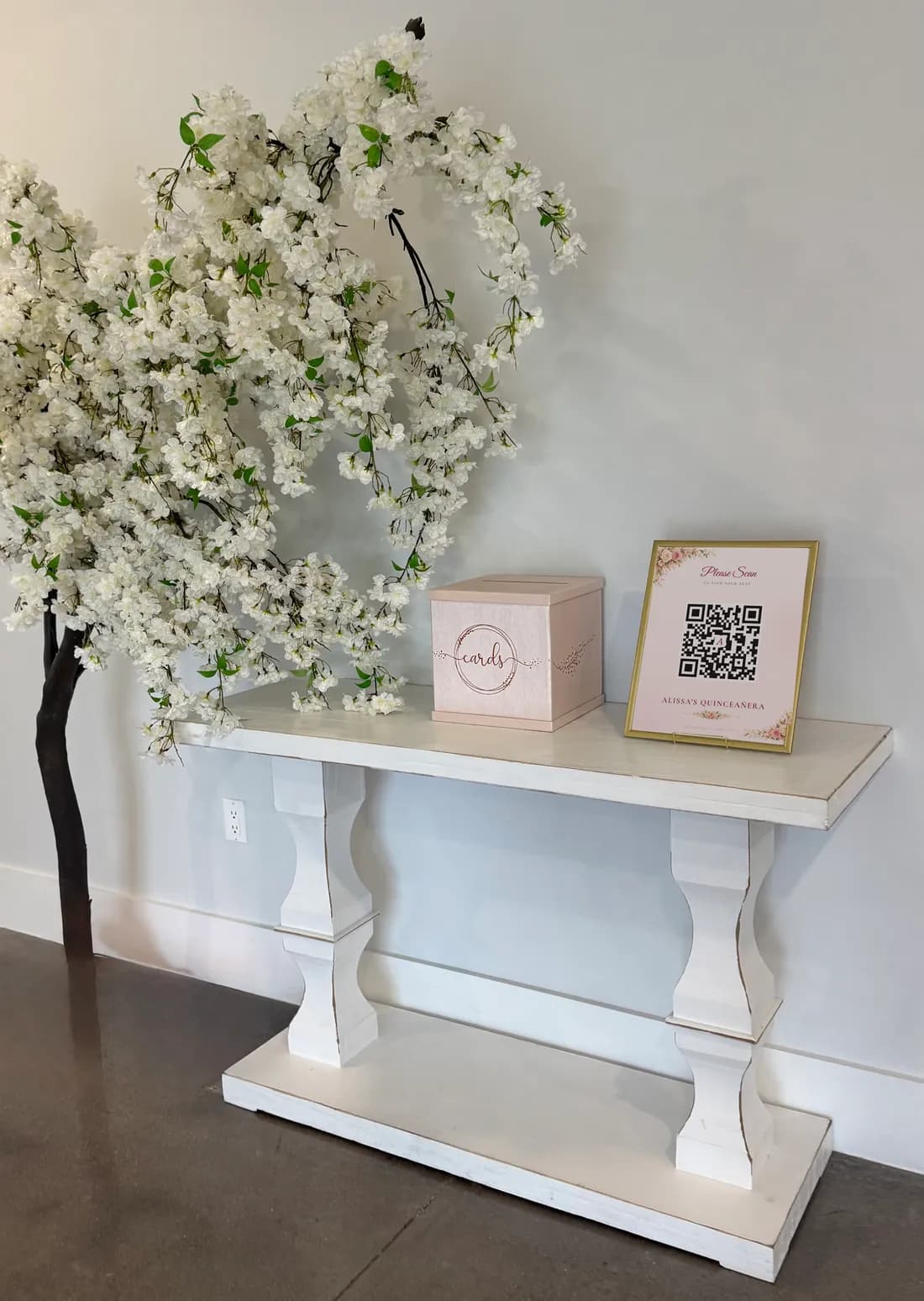 The welcome table at the entrance: a blossom tree, a card box and a framed Seatella QR code sign that says Please Scan to find your seat