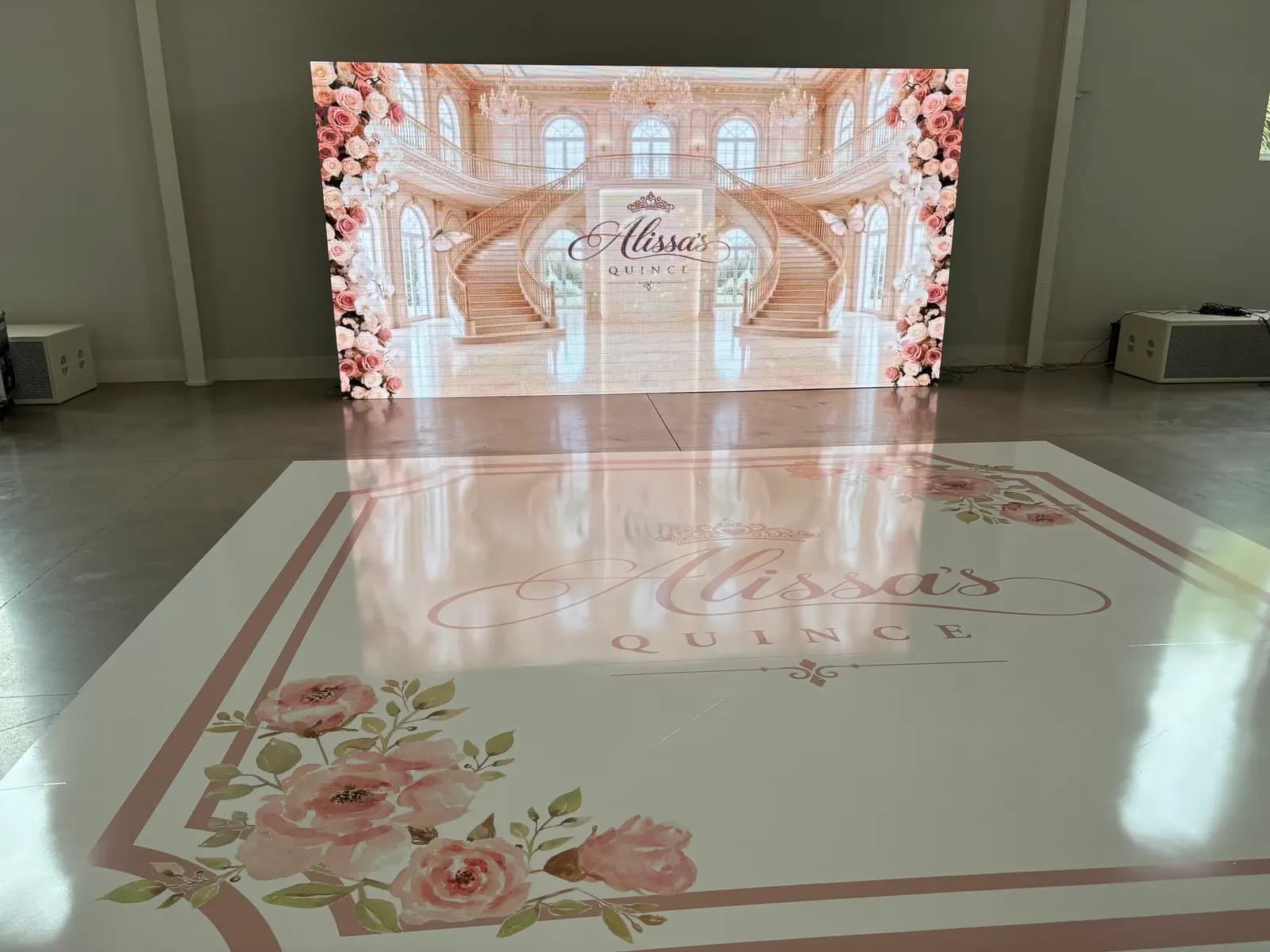 The hall at The White Orchid before the party, with an LED wall and a custom dance floor that read “Alissa’s Quince”